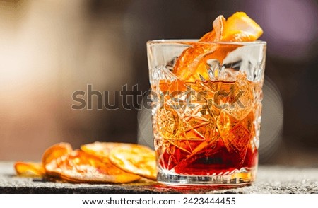 Delicious old fashion cocktail in the etched glass with ice and orange slices, dark wooden background. Shallow dof Royalty-Free Stock Photo #2423444455