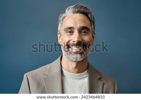 Happy middle aged 50 years old professional business man, smiling older executive ceo manager, mature Indian entrepreneur standing in office work on grey wall looking at camera, headshot portrait. Royalty-Free Stock Photo #2423464833