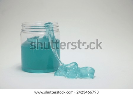 
Jar with blue slime on isolated white background. Sticky and moldable dough for children to play with. Entertainment for kids. Copy space.