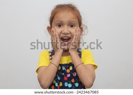 Young child's wow smile expression touching her cheeks in white background. Beautiful young girl with brown hair. Expression stock photograph.