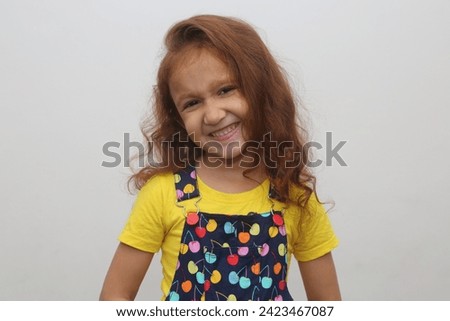 Young child's beautiful smile expression in white background. Beautiful young girl with brown hair. Expression stock photograph.