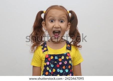 Young child's surprise expression in white background. Beautiful young girl with brown hair. Expression stock photograph.