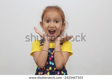 Young child's big wow smile expression in white background. Beautiful young girl with brown hair. Expression stock photograph.