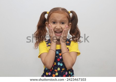Young child's wow smile expression in white background. Beautiful young girl with brown hair. Expression stock photograph.
