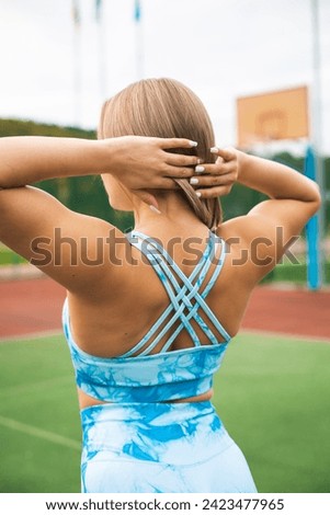 Photo of concentrated young sports woman in sportswear on stadium outdoors make sport stretching exercises.