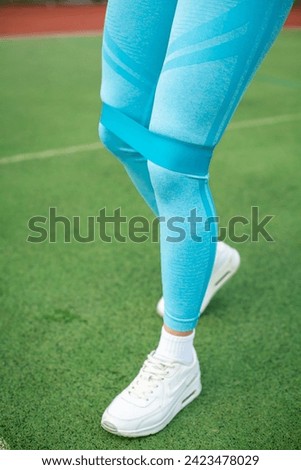 Photo of concentrated young sports woman in sportswear on stadium outdoors make sport stretching exercises.