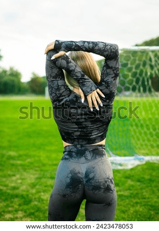 Photo of fit girl in black sportswear stretching on stadium outdoors make sport stretching exercises.