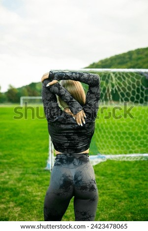 Photo of fit girl in black sportswear stretching on stadium outdoors make sport stretching exercises.