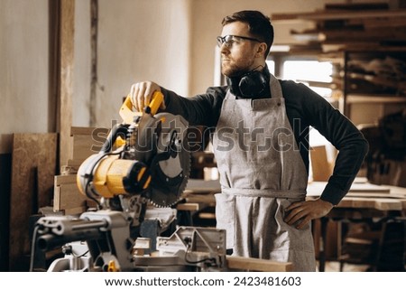 Carpenter working with wood and saw in the manufacturing industry Royalty-Free Stock Photo #2423481603