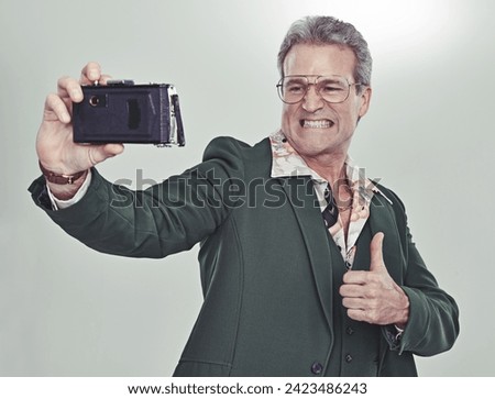 Senior man, fashion and selfie with thumbs up for good job, winning or photography on a gray studio background. Mature person in retro or vintage style and like emoji or yes sign for photo or picture