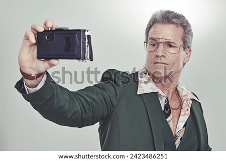 Mature man, fashion and selfie with camera in photography, memory or cool style on a gray studio background. Senior, male person with glasses and posing for photo, picture or trend in formal clothing