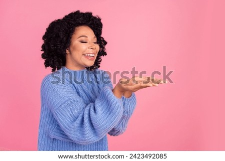 Photo portrait of pretty young girl palms hold empty space wear trendy blue knitted outfit isolated on pink color background
