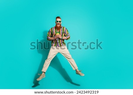Full body length size photo of jumping young macho with red hair hold yellow pineapple cup for juice isolated on cyan color background