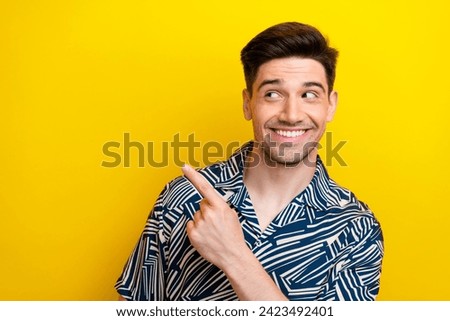 Photo of cheerful man with stylish hairdo dressed blue clothes look direcitng at poster empty space isolated on yellow color background
