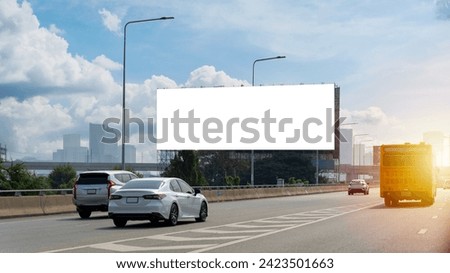 A large, blank billboard on the side of a highway. The billboard is white. It is located in a rural area, with trees and grass in the background. The sun is shining and the sky is blue, clipping path.