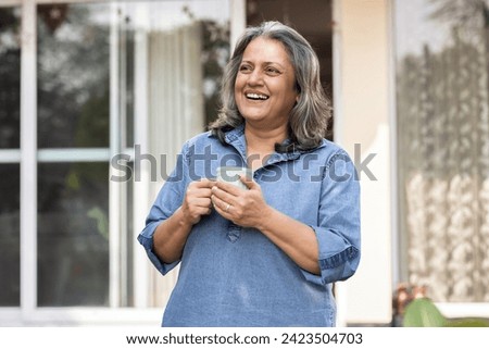 Happy Old Woman drinking coffee at backyard.