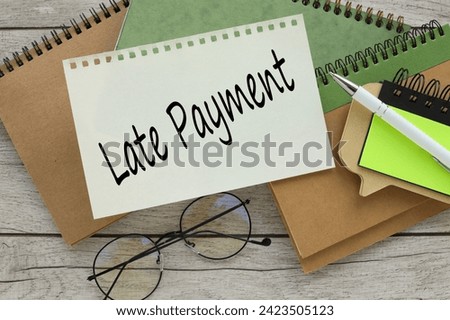 Business different notepads on the table. text on the page near the glasses LATE PAYMENT