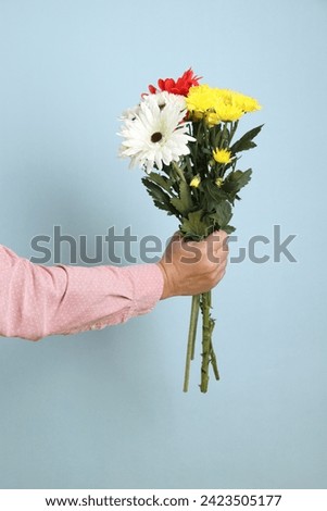 Hand of asian man with gesture of holding a bouquet of flowers isolated on blue background. St Valentine's Day, Women's Day, Birthday