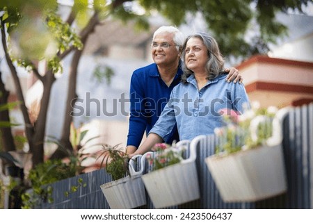 Smiling Indian senior couple with hands clasped looking away Royalty-Free Stock Photo #2423506437