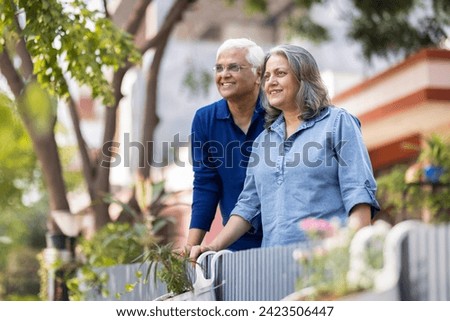 Smiling Indian senior couple with hands clasped looking away Royalty-Free Stock Photo #2423506447