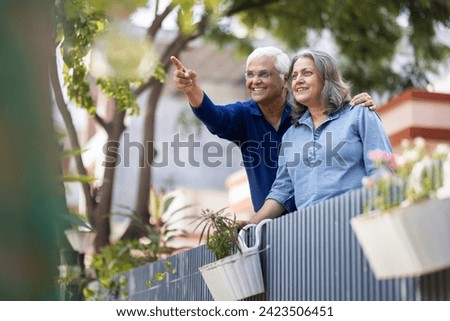 Smiling Indian senior couple with hands clasped looking away Royalty-Free Stock Photo #2423506451