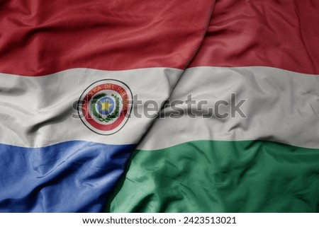 big waving national colorful flag of hungary and national flag of paraguay . macro