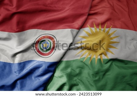 big waving national colorful flag of kurdistan and national flag of paraguay . macro