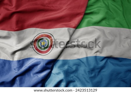 big waving national colorful flag of sierra leone and national flag of paraguay . macro