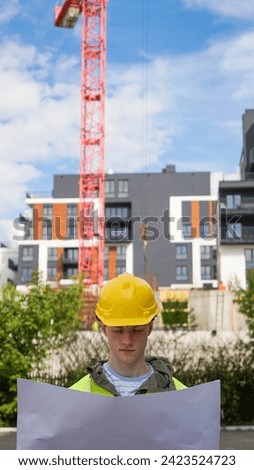 Construction worker looking at construction blueprint at a construction site - Stock photo