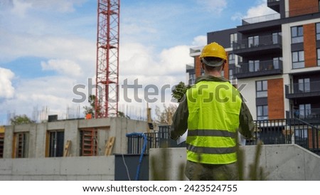 Construction worker looking at construction blueprint at a construction site - Stock photo