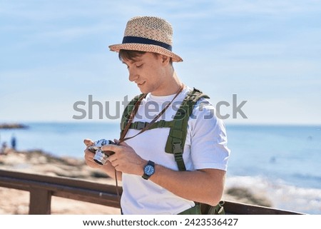 Young caucasian man tourist holding vintage camera at seaside