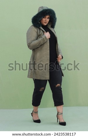 beautiful female model posing in green long coat leather jacket with stylish bun and hat