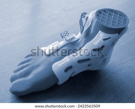 Medicine splint corset prosthesis langet for foot and model human foot printed on 3D printer from molten plastic. Medical orthosis, fixator, plastic overlay for leg and human leg created on 3D printer Royalty-Free Stock Photo #2423563509