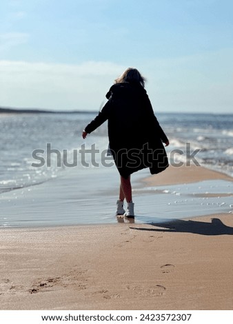 Small waves framing the shore, creating the impression of softness and harmony. Silhouette of a girl. There is space for text.