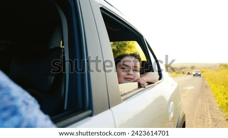 child girl face looks smiling from car out window, summer trip with family by car, car, road trip way vacation, daughter, little girl playing, catching sun glare, cheerful girl smiling, smile child