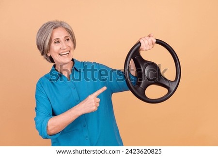 Portrait of funny person wear stylish shirt directing look at steering wheel in arm recommend service isolated on beige color background