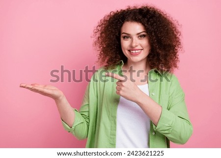 Photo portrait of attractive young woman palm hold point empty space wear trendy green clothes isolated on pink color background