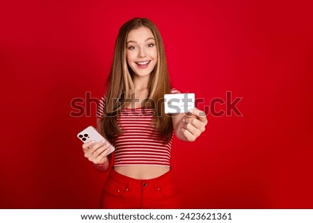 Photo of excited sweet girl wear striped top enjoying online banking modern device showing you credit card isolated red color background