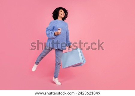 Full body photo of attractive young woman shopper eshop keep balance dressed stylish blue knitted clothes isolated on pink color background