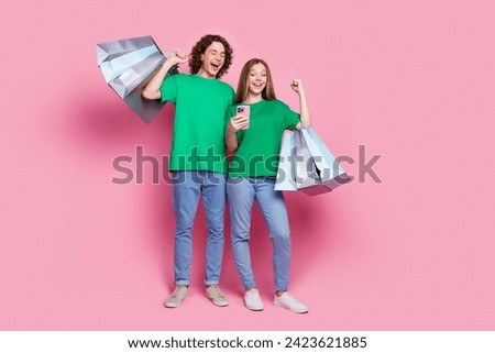 Full body size photo extra prize winners couple teenagers like their free bonus eshopping gifts in phone isolated on pink color background