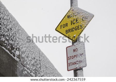 The "Watch for Ice on Bridges" sign in the snow. 