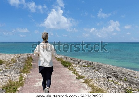 A woman jogging along the coast of Okinawa Royalty-Free Stock Photo #2423690953
