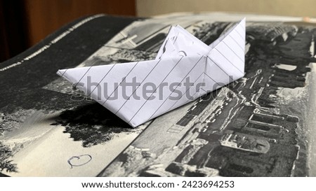 origami paper boat, placed in an old magazine book