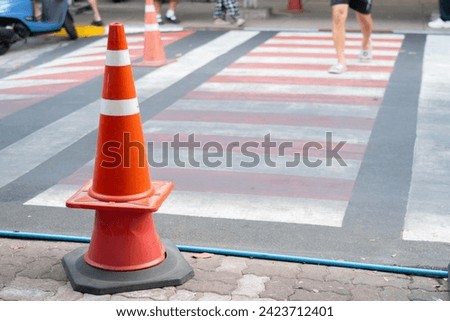 Shot view of blurred confident male walking on city crossroad and selective focus at traffic cones. Traffic sign concept.