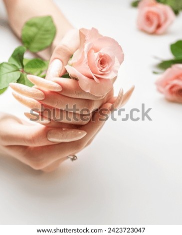 Female Hands on a white background with beautiful pearl manicure and pink rose flowers