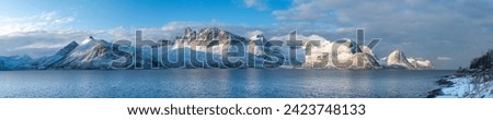 Panorama with Øyfjorden,  the snowy mountains from Senja, named Segla, Kongan and Skultran. interesting winter mood with blue and cloudy sky and steep rocky mountains in Norway Royalty-Free Stock Photo #2423748133