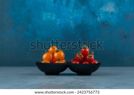 Red and yellow cherry tomatoes on grey background. High quality photo