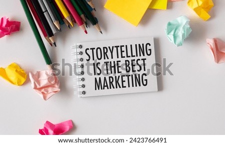 Notepad with text STORYTELLING IS THE BEST MARKETING on a white table with pencils and crumpled paper. The concept of storytelling in marketing and advertising. Top view, flat lay.