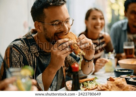 Young man eating tacos during a lunch with friends in Mexican restaurant. 