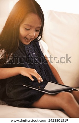 Little girl, child and tablet on sofa in entertainment, elearning or social media with lens flare at home. Face of female person or kid browsing on technology or reading ebook in living room at house